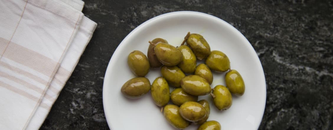 Gröna oliver i vit skål
