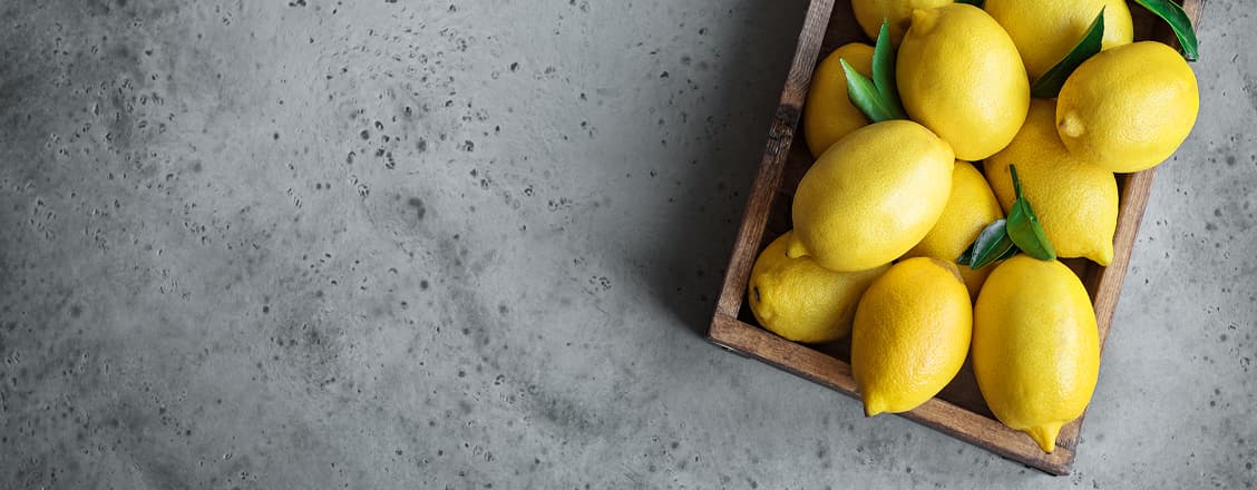 Citroner i en skål på grå bakgrund