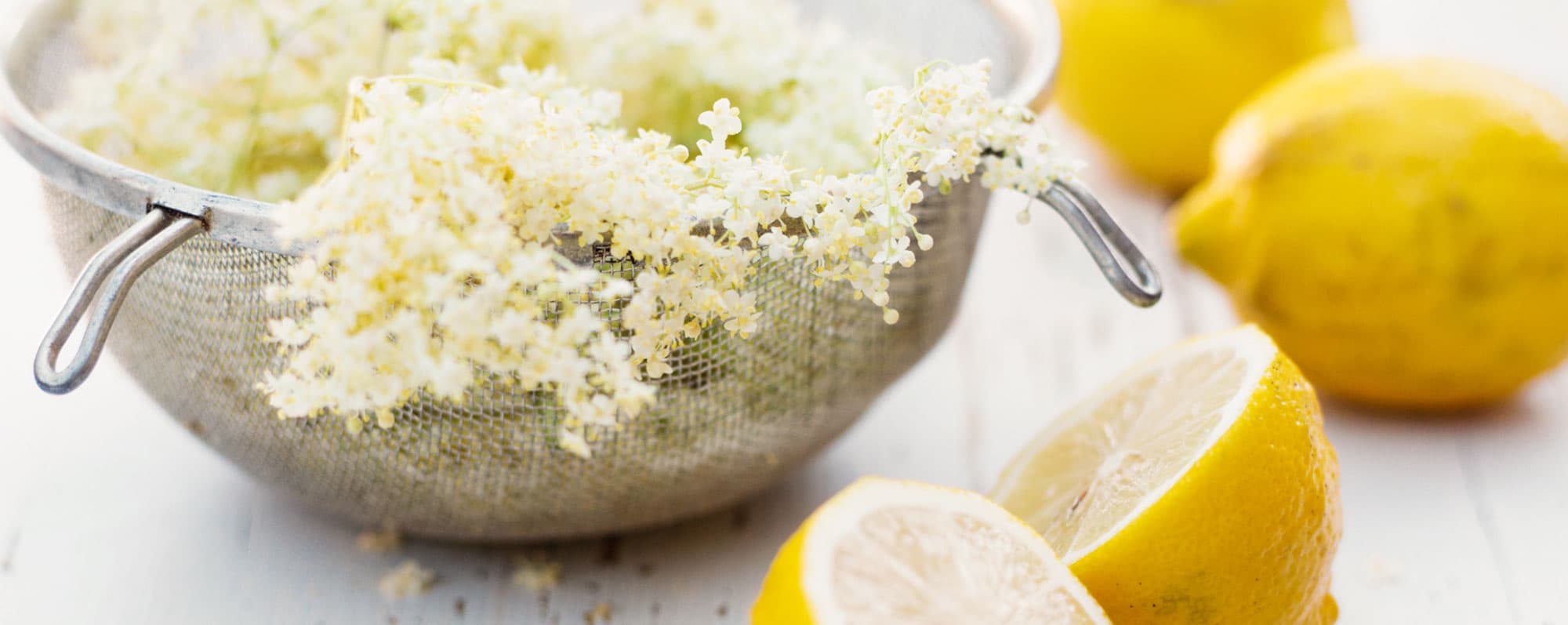 Sil med fläderblommor vid sidan av citronhalvor.