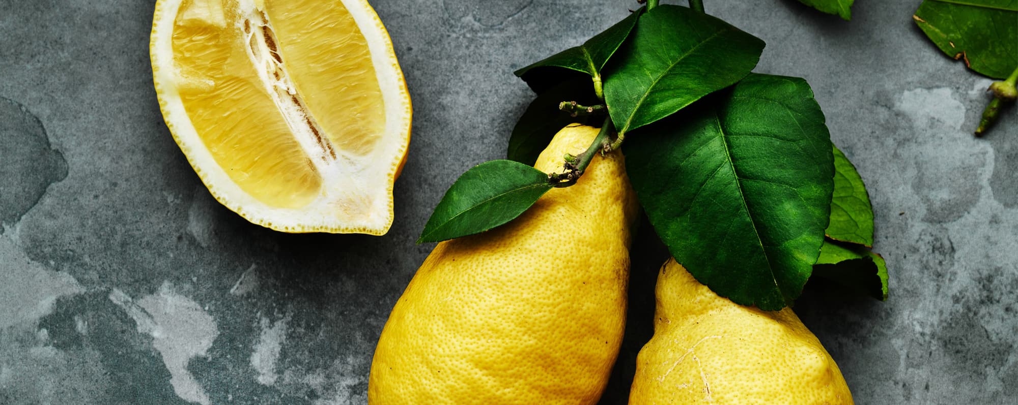 En delad citron och två hela med grönt blad.