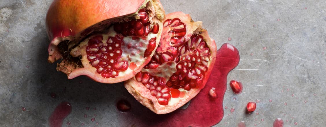 Uppskuret granatäpple på grå bakgrund