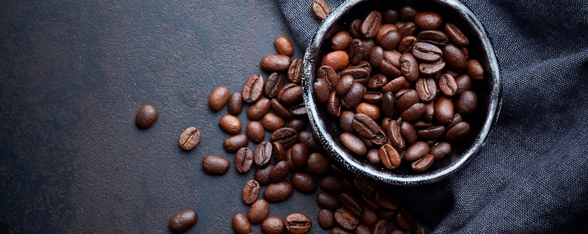 Närbild på kaffebönor uthällda på bord.